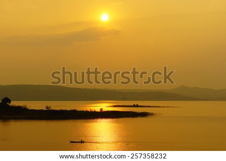 Abstract Vietnamese rural at sunset, sun on yellow sky, vibrant color, silhouette of people rowing a row boat on Nam Ka Lake, Dakak, Vietnam, house on water, make amazing landscape of Viet Nam travel
