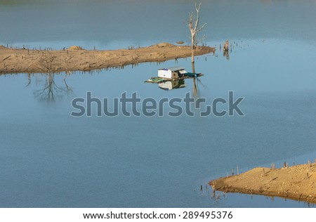 Harmony landscape of Asia countryside, lonely floating house on water, beautiful Nam Ka lake at Daklak, Viet nam. Reflection of dry tree, home on river make beautiful scene