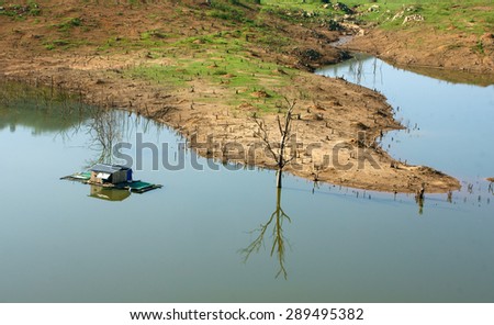 Harmony landscape of Asia countryside, lonely floating house on water, beautiful Nam Ka lake at Daklak, Viet nam. Reflection of dry tree, home on river make beautiful scene