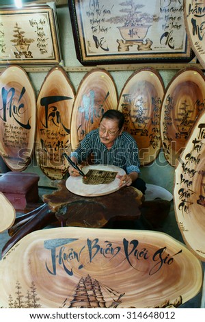 QUY NHON, VIET NAM- AUG 23: Vietnamese artist doing wood engraving by fire pen, man engrave Han Mac Tu poem at souveir shop of Genh Rang tourist area, a famous poet, Quynhon, Vietnam, Aug 23, 2015