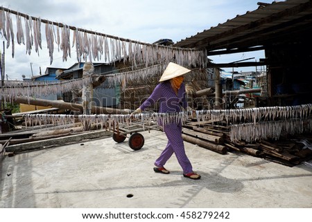 CAMAU, VIET NAM- JULY 16, 2016: Vietnamese woman dry seafood at Ca Mau fishing village, Mekong Delta. Dried fish is popular Vietnam food, can store for long time