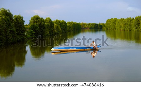 CA MAU, VIET NAM- JULY 16, 2016: Vietnamese man catch fish on river, people and row boat reflect on water, beautiful green tree from mangrove forest make wonderful scene in evening at Mekong Delta