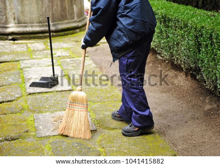 Sweeper, municipal cleaning worker sweeping autumn leaves in the garden