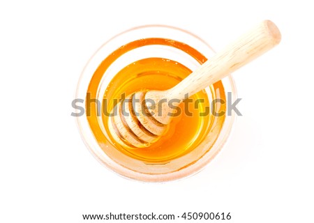 Honey with wooden honey dipper in small bowl on wooden table