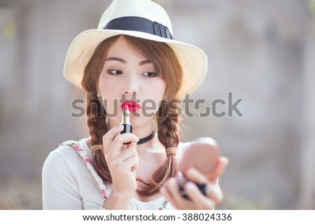 portrait of teenage asian girl applying lipstick, focus on mouth.