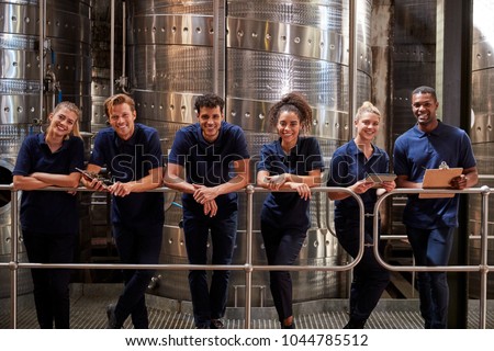 A row of staff at a wine factory smiling to camera, close up