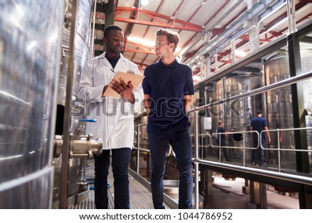 Two male staff members make an inspection at a wine factory