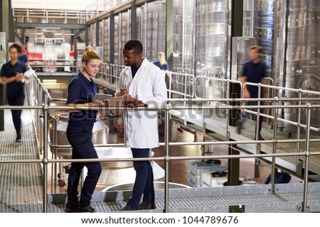 Two staff talking in a modern winemaking factory, close up