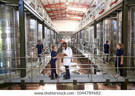 Two staff talking on gangway in a modern winemaking factory