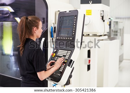 Female Engineer Operating CNC Machinery On Factory Floor