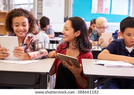 Teacher among kids with computers in elementary school class