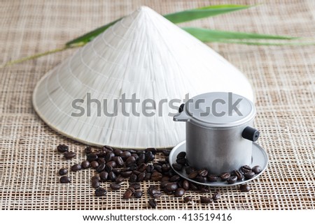 Vietnamese coffee brewing pot with coffee beans and conical hat