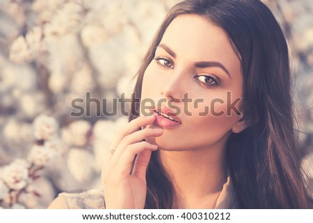 Spring fashion girl outdoors portrait in blooming trees. Beauty Romantic woman in flowers. Sensual Lady. Beautiful Woman Enjoying Nature. Romantic beauty in fantasy orchard
