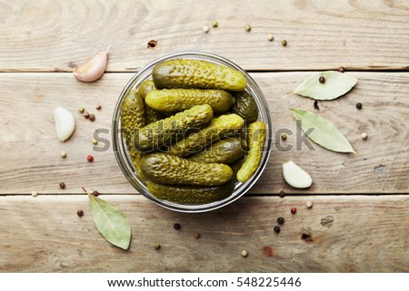 Pickled gherkins or cucumbers in bowl on wooden rustic table from above.