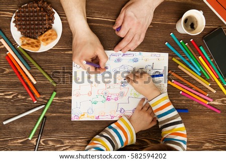 Happy family. Children's and Father hands painted with felt-tip pens. Top view creative photo of hands little boy and Father on vintage brown wooden table.