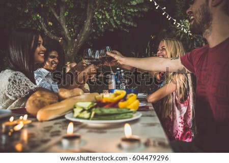 Group of friends making barbecue in the backyard at dinner time