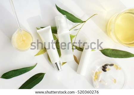 Cosmetic bottle containers with green herbal leaves, Blank label for branding mock-up, Natural beauty product concept.