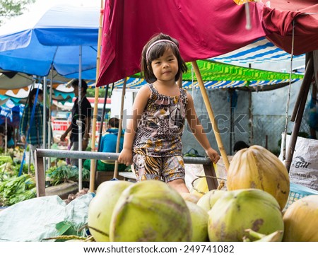 Vinh Long, Vietnam - Nov 30, 2014: Unidentified child plays alone among a lot of fruits at Vinh Long market, Mekong delta. Almost local people at market are poverty