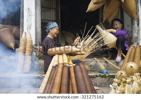 Hung Yen, Vietnam - July 26, 2015: Old women weaves bamboo fish trap at Vietnamese traditional crafts village Thu Sy, Hung Yen province.