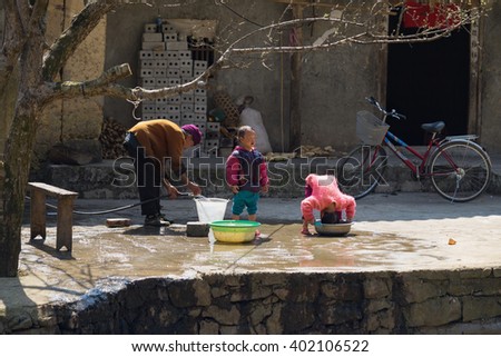 Ha Giang, Vietnam - Feb 14, 2016: Hmong grandmother help her children to wash their hair in front of the house in Dong Van district in sunny day