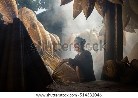 Hung Yen, Vietnam - July 9, 2016: Old house yard with many bamboo fish trap and female craftsman making traditional bamboo fish trap at her old house in Thu Sy trade village