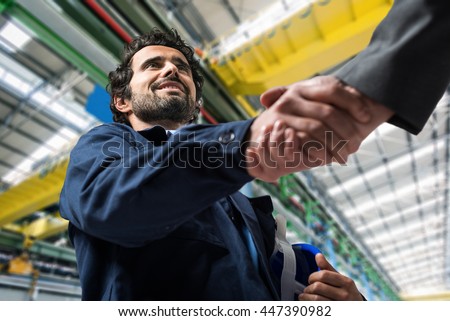 Portrait of a man giving an handshake in an industrial facility