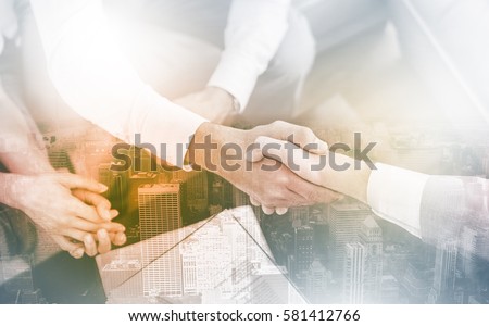 Salesman shaking hands with client with contract on the coffee table