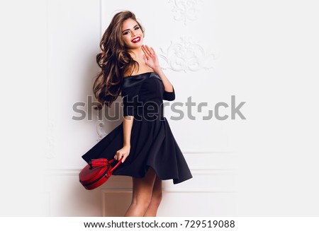 https://thumb9.shutterstock.com/display_pic_with_logo/2196125/729519088/stock-photo-amazing-luxury-seductive-woman-in-stylish-black-party-dress-posing-on-white-wall-red-hand-bag-729519088.jpg
