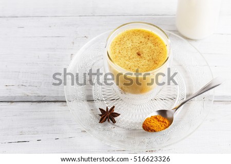 Golden turmeric latte over white wooden table with copyspace