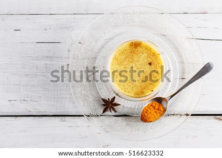 Top view image of turmeric latte over white wooden table with copyspace