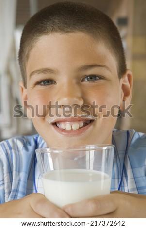 Happy young boy drinking glass of milk