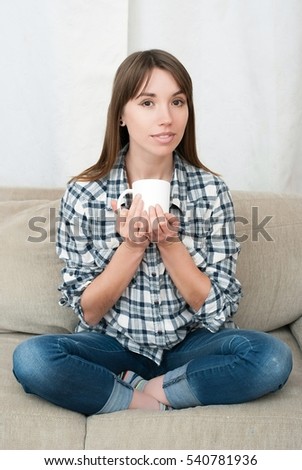 https://thumb9.shutterstock.com/display_pic_with_logo/228151/540781936/stock-photo-portrait-of-young-woman-sitting-on-couch-in-her-living-room-and-drinking-coffee-or-tea-attractive-540781936.jpg