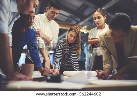 Young male and female architect colleagues drawing graphic planning of interior creation project cooperating with talented teacher giving advice and correcting mistakes during training lesson