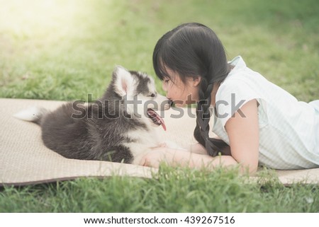 Beautiful asian girl playing with siberian husky puppy in the park,vintage filter