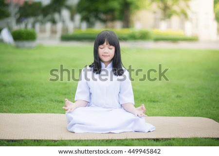 Beautiful Asian girl wearing white dress meditating in lotus position