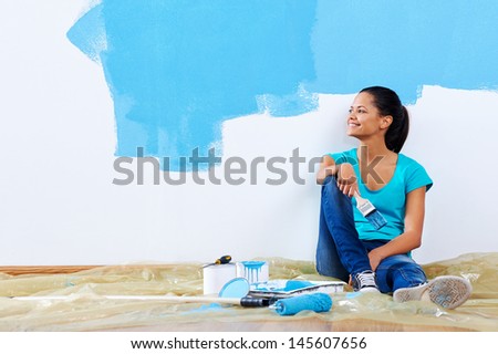 confident young woman portrait while painting new apartment renovating with blue color paint - Woman Home Decorating confident young woman portrait while painting new apartment renovating with blue color paint - Woman Home Decorating