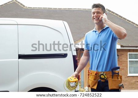 Electrician Standing Next To Van Talking On Mobile Phone