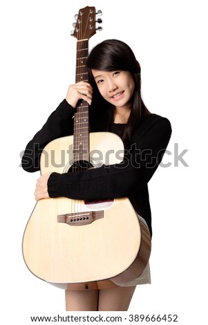 Teenage asain girl hugging her acoustic guitar, Isolated over white
