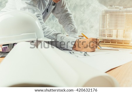 Architect working on blueprint. Architects workplace - architectural project, blueprints, ruler, helmet and divider. Construction concept. Engineering tools