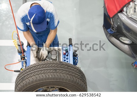mechanic repairman making tyre fitting screwing out a wheel nipple