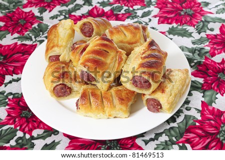a plate of sausage rolls traditional british christmas food on a festive tablecloth - British Christmas Traditions a plate of sausage rolls traditional british christmas food on a festive tablecloth - British Christmas Traditions