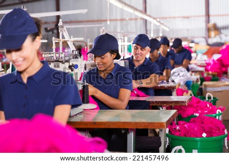 group multiracial factory workers sewing in clothing factory