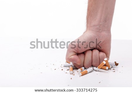 Stop smoking. Close up of male hand breaking cigarettes with his fist. Isolated and copy space in left side
