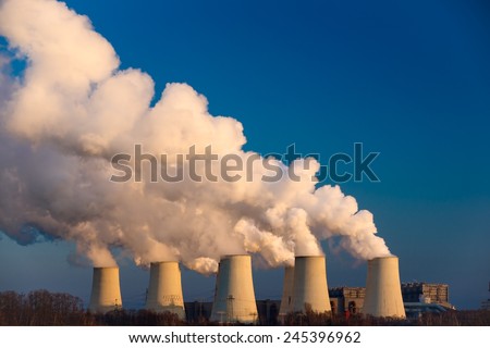 Smoking pipes of thermal power plant against blue sky on sunset