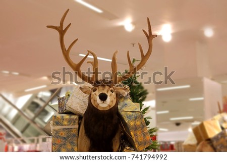 Fake,stuffed reindeer,carrying wrapped present boxes,as the symbol of Christmas gifting,as decoration in a big store.