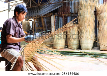 Vinh Long city, Vietnam - 06 May 02, 2015: Unknown, An Asian man weaving handicraft basket from bamboo. The fruit trader on floating market in the Mekong Delta will need the baskets like these