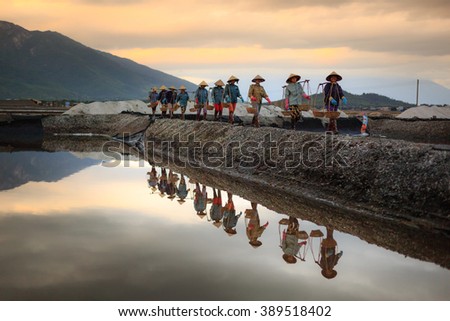 Ninh Thuan Province, Vietnam - February 28, 2016 :the women are working on salt field at dawn. Salt field Hon Khoi in Nha Trang, Viet Nam. Workers transporting salt from the fields Hon Khoi, Viet Nam.