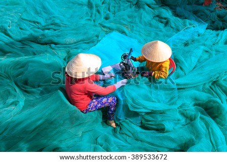 Ninh Thuan Province, Vietnam - February 27, 2016: two women are sewing fishing nets in fishing village in Vinh Hy Bay, Phan Rang province. They work hard all day to sew large fishing nets