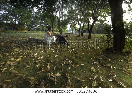 Flamingo Dai Lai, Vinh Phuc province, Vietnam - October 13, 2016: woman sitting reading relaxing on the lawn full of yellow leaves falling off into the sunset