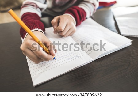 Child write in a notebook. Close up hand and pen